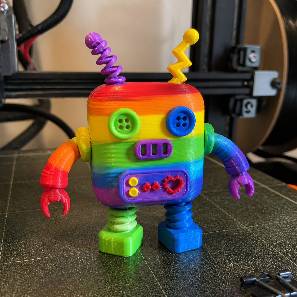 Rainbow Bot, a colorful 3D-printed robot Artwork Figure standing on a printer build plate